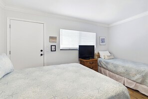A bedroom with two beds, a television, and a window with blinds. - Updated Oceanfront Condo With Two Private Balconies! (St. Augustine)