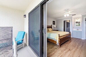 A bedroom with a bed, a ceiling fan, and a bathroom with a sink and mirror. - Updated Oceanfront Condo With Two Private Balconies! (St. Augustine)