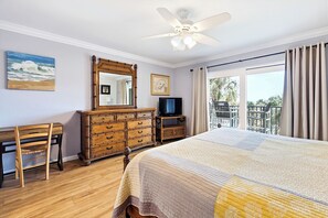 A hotel room with a bed, a dresser, a television, a chair, a ceiling fan, and a balcony with a view. - Updated Oceanfront Condo With Two Private Balconies! (St. Augustine)