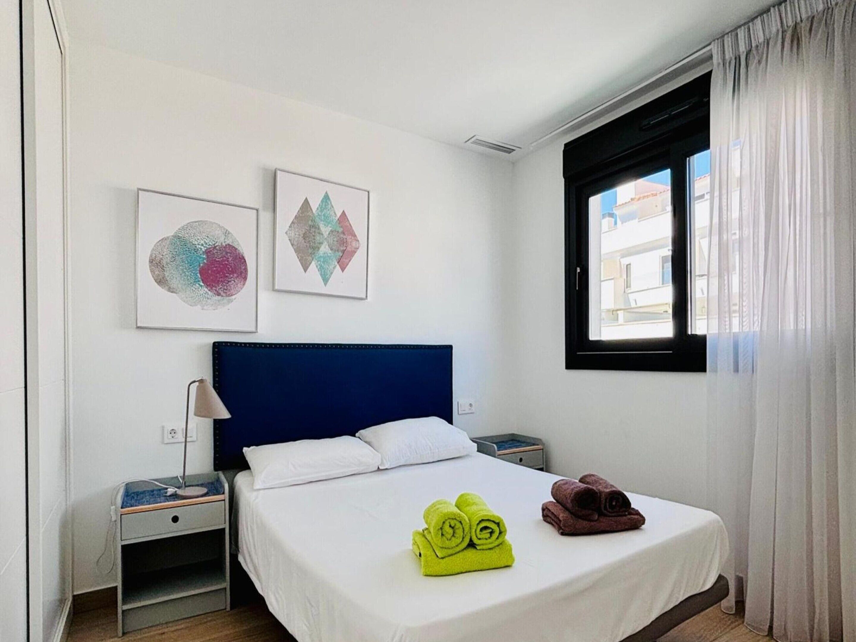 A hotel room with a bed, two nightstands, a lamp, and artwork on the wall.