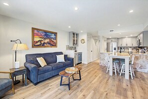 A modern living room with a sofa, coffee table, and a painting of sea turtles. - Beautifully renovated townhouse style condo with amazing ocean views! (St. Augustine)