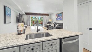 A modern kitchen with a marble countertop, stainless steel sink, and built-in dishwasher.