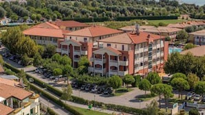 A residential complex with multiple buildings, a parking area, and a view of the sea.