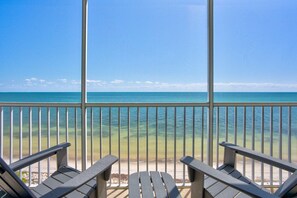 A balcony with a view of the ocean, two Adirondack chairs, and a clear sky. - Sandpiper Cove updated 2bed/2bath beachfront condo with shared pool (Marathon)