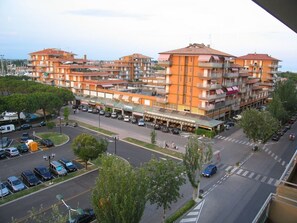 A multi-story residential building with balconies, a central courtyard, and a parking lot. - Apartment in Caorle Near Sandy Beaches (Caorle)