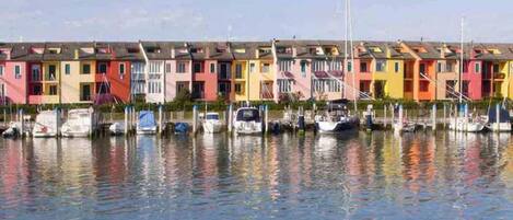 A row of colorful houses by a calm waterfront with boats docked in the water.