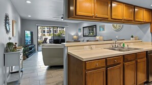 Una cucina moderna con mobili in legno, un'isola grande e vista sull'area living.