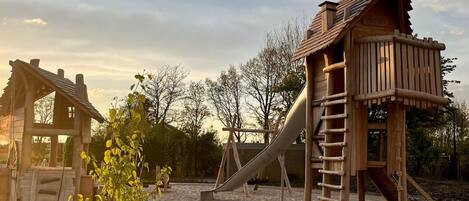 A playground with wooden play structures including a slide and a climbing ladder.