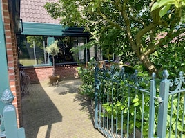 A covered patio area with a brick wall, a metal gate, and potted plants.