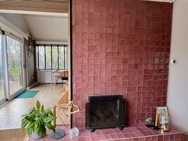 Una sala de estar moderna con una chimenea de baldosas rojas, una silla de madera y una planta en maceta.