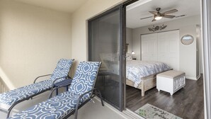 Une pièce comprenant un lit, un ventilateur de plafond et deux fauteuils.