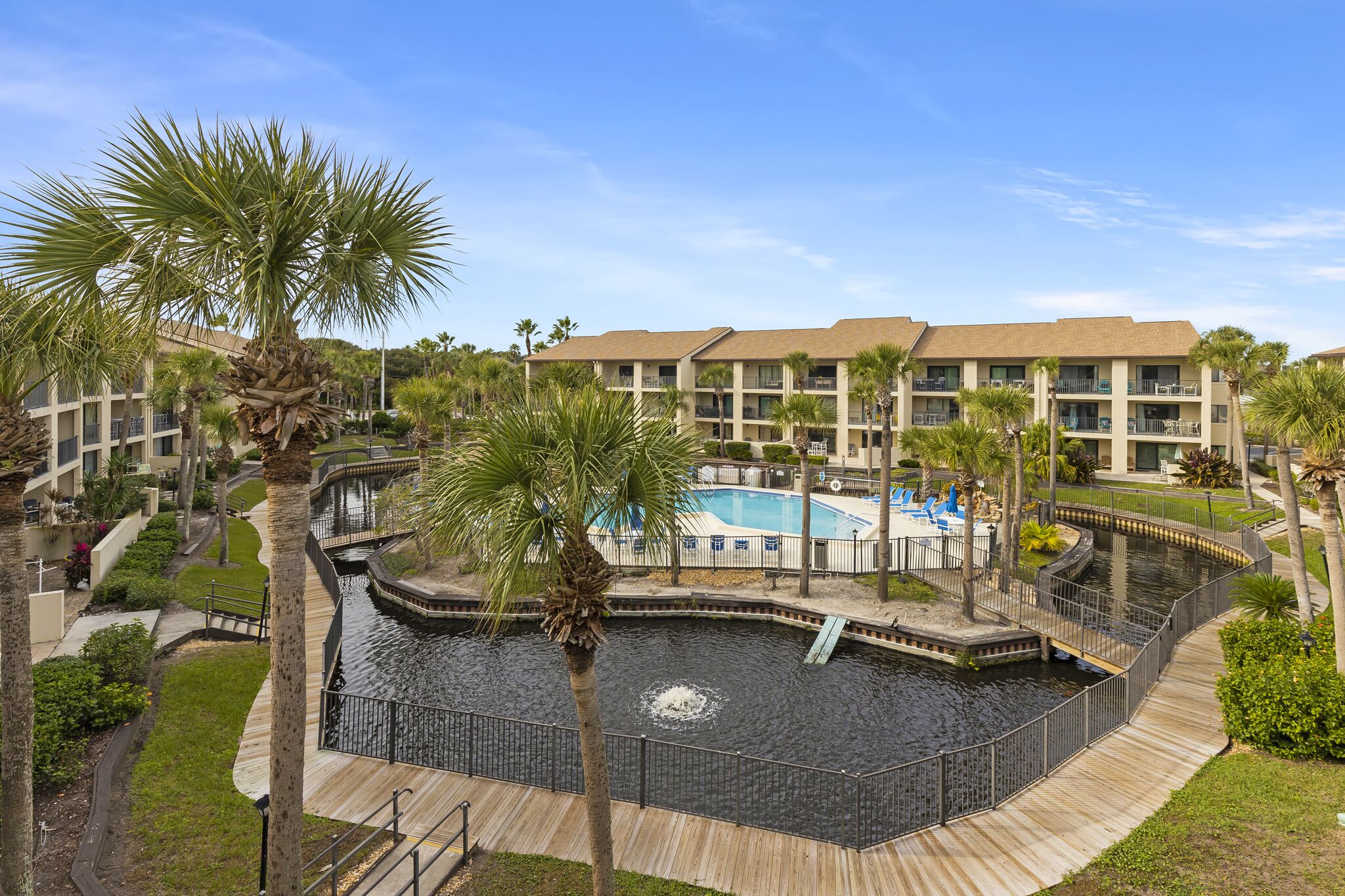 Un resort con piscina, palme e un pontile in legno.