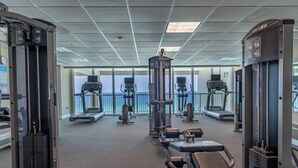 Une salle de sport équipée de divers appareils d’exercice, de tapis de course et d’un espace dédié à la musculation.