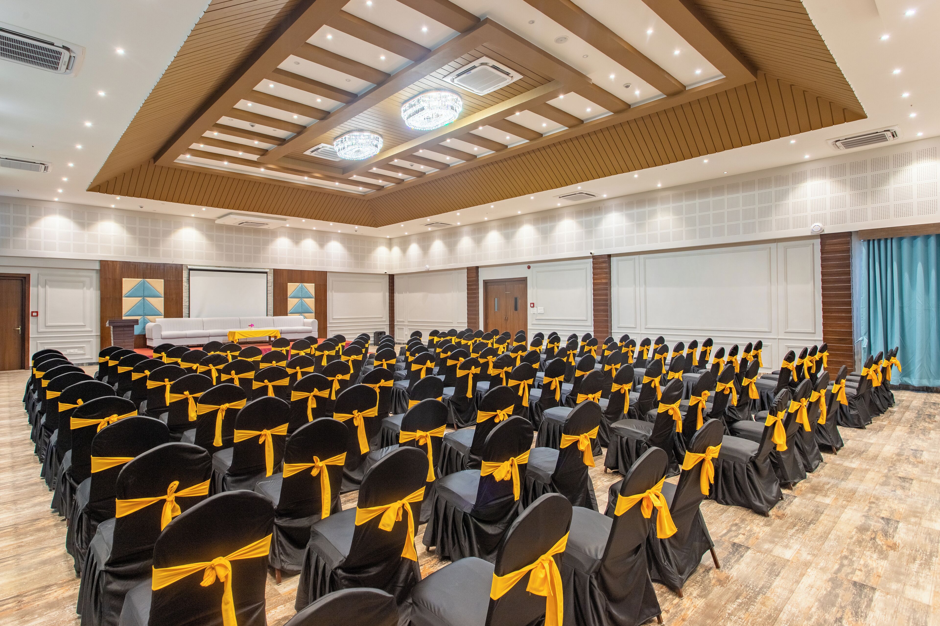 Een vergaderzaal met rijen stoelen, een podium en een groot scherm.