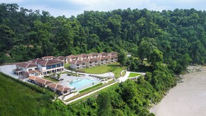 Vista aérea de un resort con varias construcciones, una piscina y una playa.