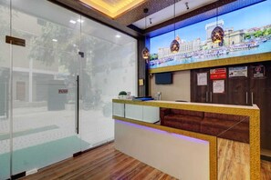 Un espace d’accueil doté d’une cloison en verre, d’un comptoir de réception en bois et d’un grand écran numérique affichant une vue panoramique de la ville.