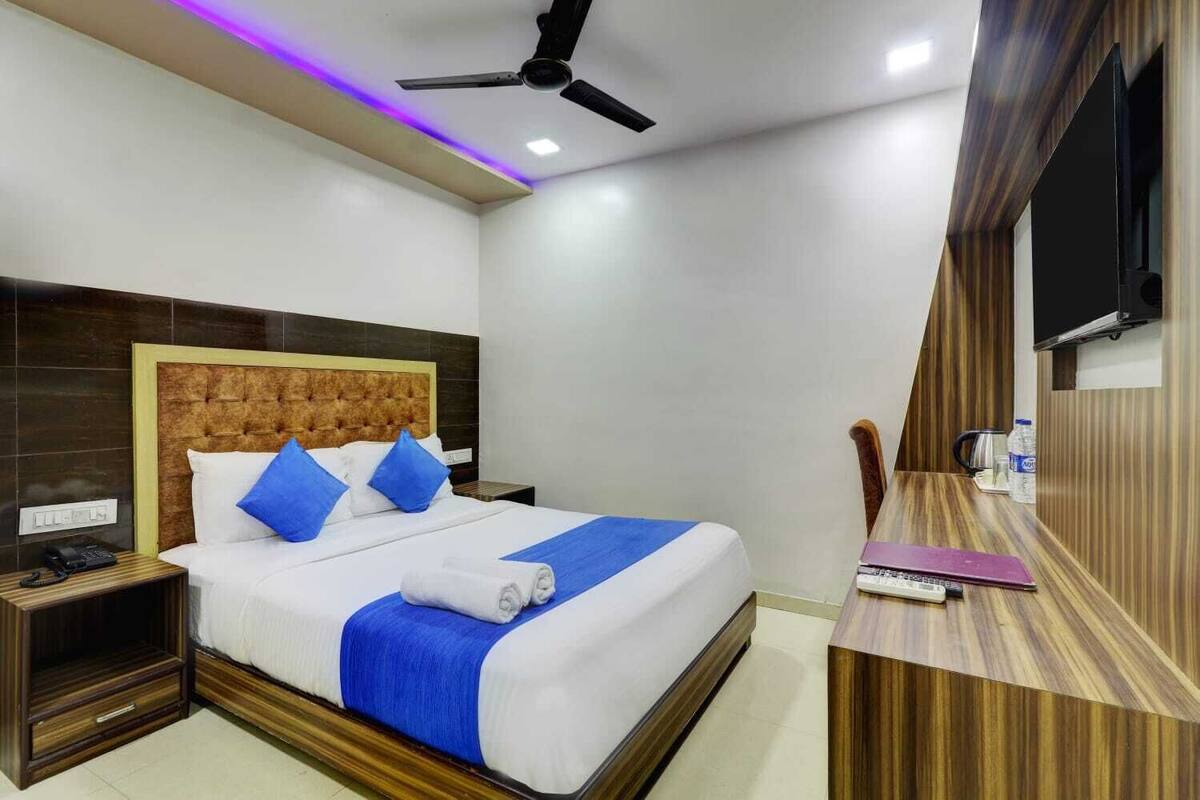 Une chambre d’hôtel comprenant un lit, une table de chevet et un bureau avec une chaise.