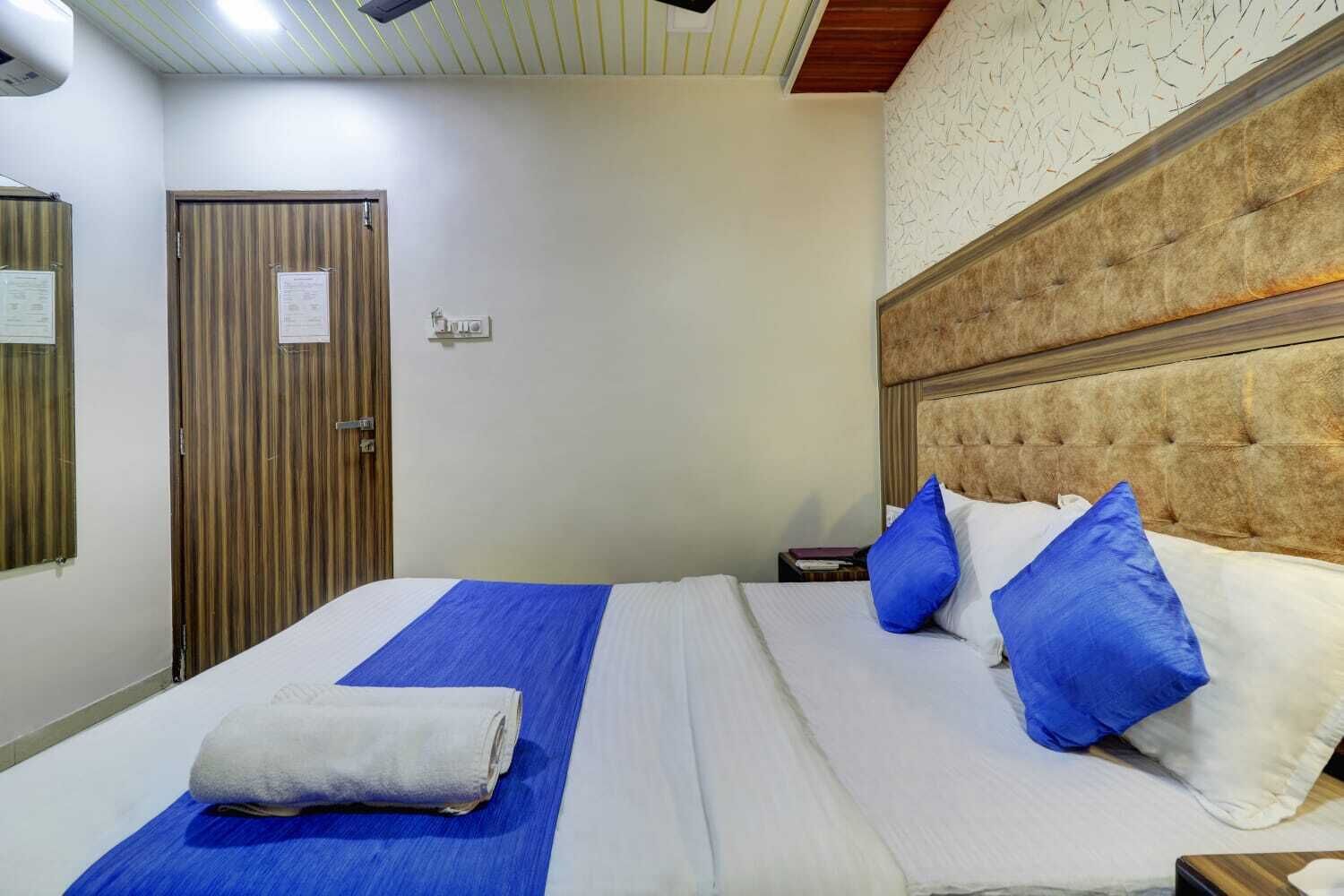 Une chambre d’hôtel avec un lit, une couvre-lit bleue, des oreillers blancs et une tête de lit.