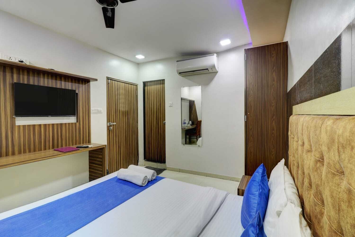 Une chambre d’hôtel comprenant un lit, un téléviseur fixé au mur, un miroir et une armoire.