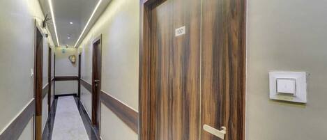 A hallway with wooden doors, numbered 107, and a light switch on the wall.