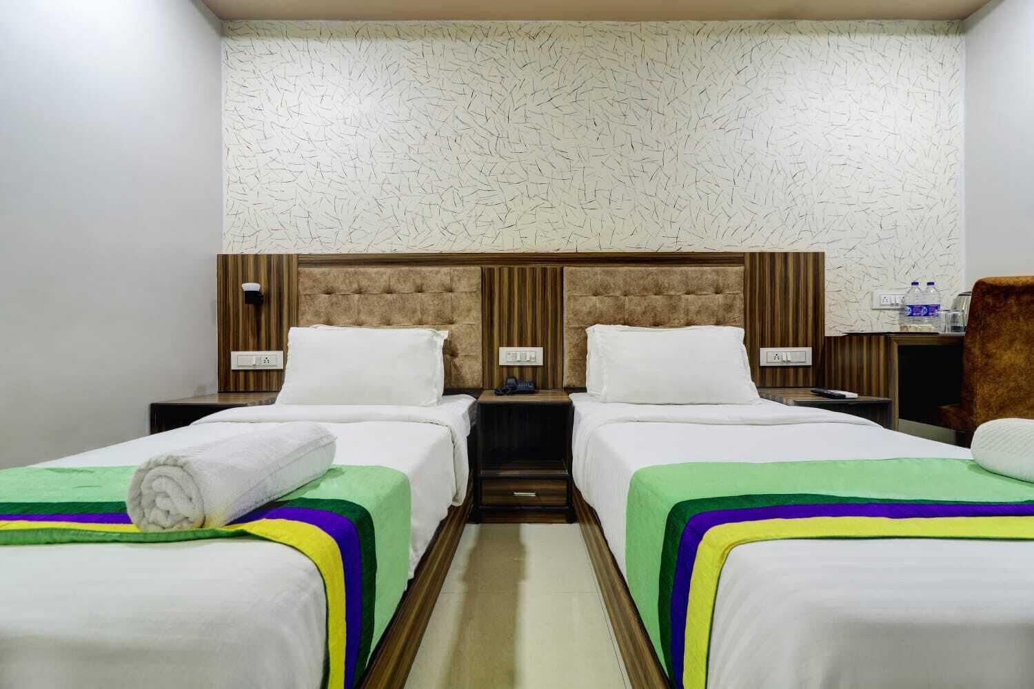 Habitació d'hotel amb dos llits, cadascun amb un capçal, una petita taula de nit i una làmpada.