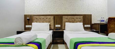 A hotel room with two beds, each with a headboard, a nightstand, and a lamp.