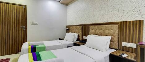 A hotel room with two beds, a wooden headboard, a patterned wall, and a red rug.