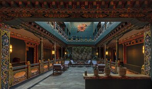 A traditional interior with ornate decorations, a central seating area, and a stone wall. - Taktsangri-La (Paro)