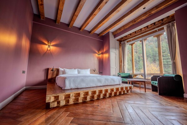 Un dormitorio con cama de madera, dos apliques, una ventana con cortinas y vistas a árboles.