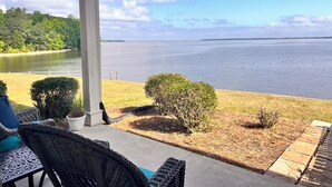 Varanda coberta com móveis de vime e vista para um lago.