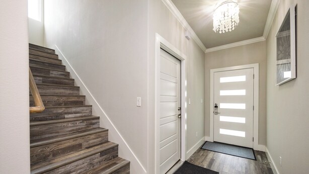Un escalier en bois mène à une porte dotée d’un panneau de verre.