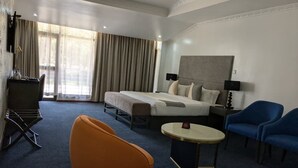 Una habitaci ón de hotel con una cama, dos sillas, una mesita pequeña y un escritorio con una lámpara.