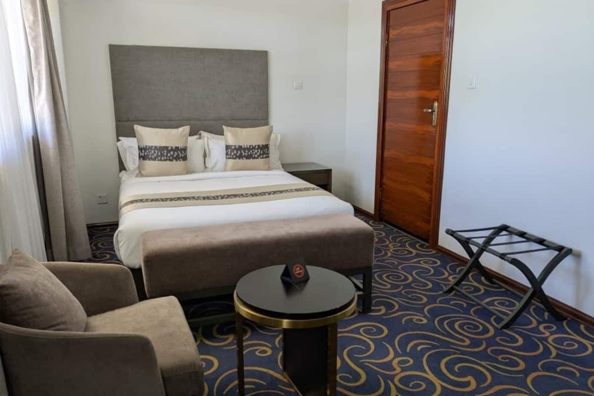 Una habitación de hotel con cama, sofá, una pequeña mesa redonda y una puerta de madera.