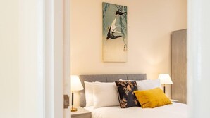 Een keurig opgemaakt slaapkamer met een bed, twee bedlampen, een nachtkastje met lades en een aan de muur hangend schilderij.