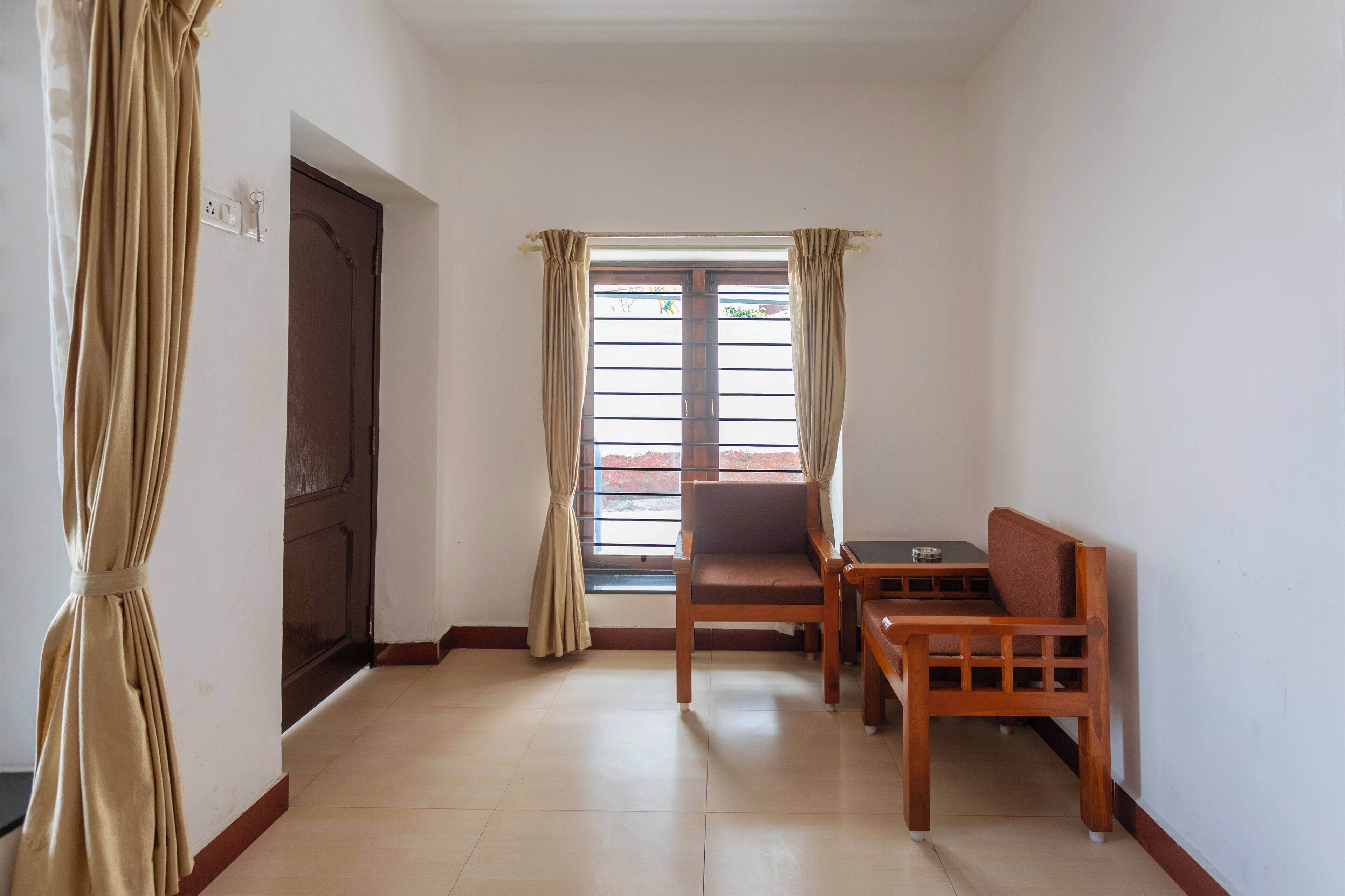 A room with a wooden bench, a table, a door, and a window with curtains.