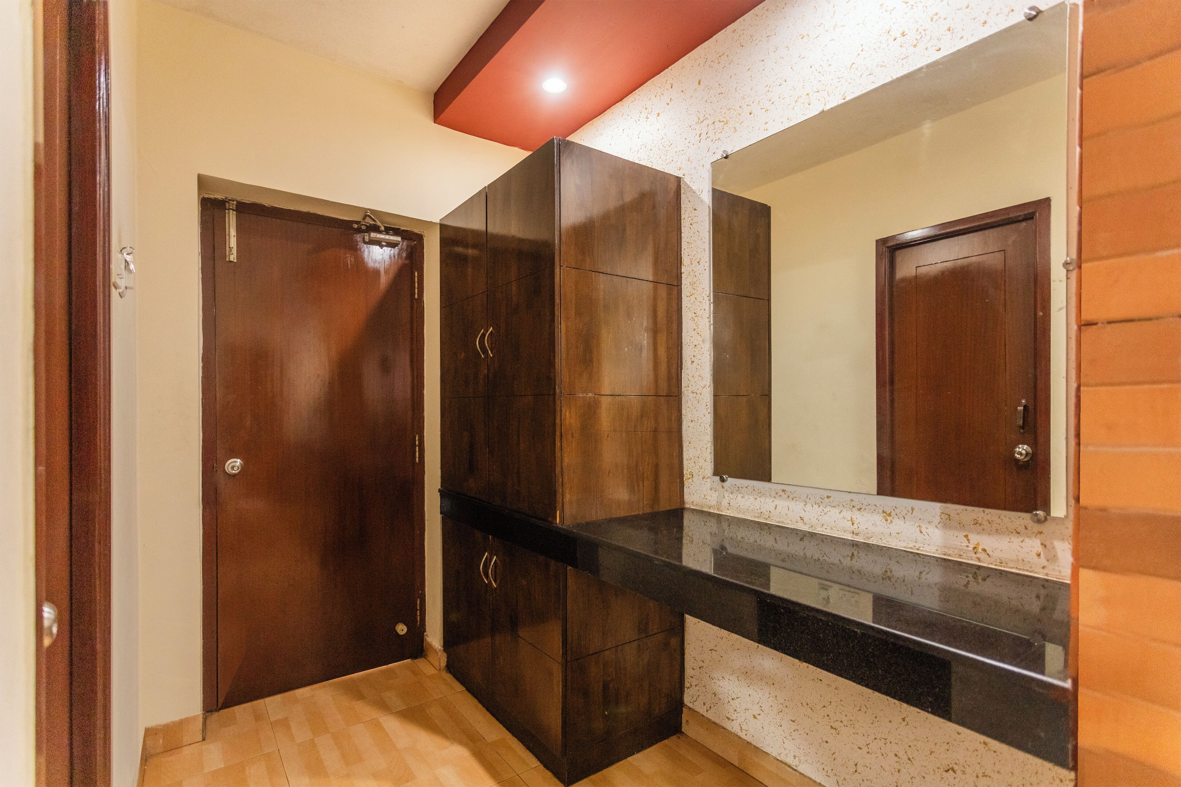 Une pièce avec une armoire en bois, un miroir et un comptoir noir.