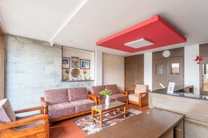 Uma sala de estar moderna com parede de pedra, móveis de madeira e uma parede em destaque vermelha.