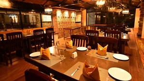 Un restaurante con mesas y sillas de madera, una pared de ladrillo y vistas al exterior.