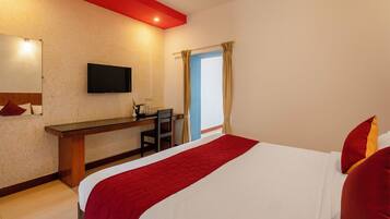 A hotel room with a bed, a desk, a chair, a television, and a window with curtains.