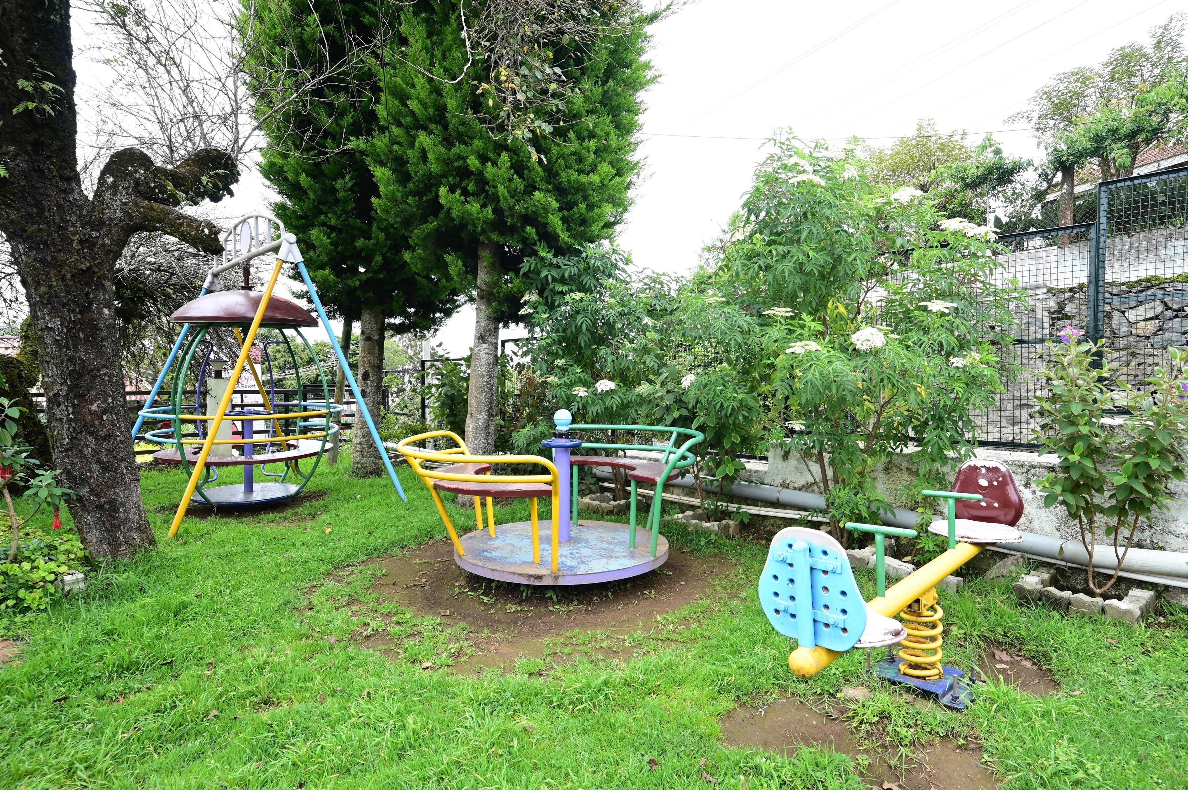 Un parque infantil con un sube y baja, un carrusel y columpios.