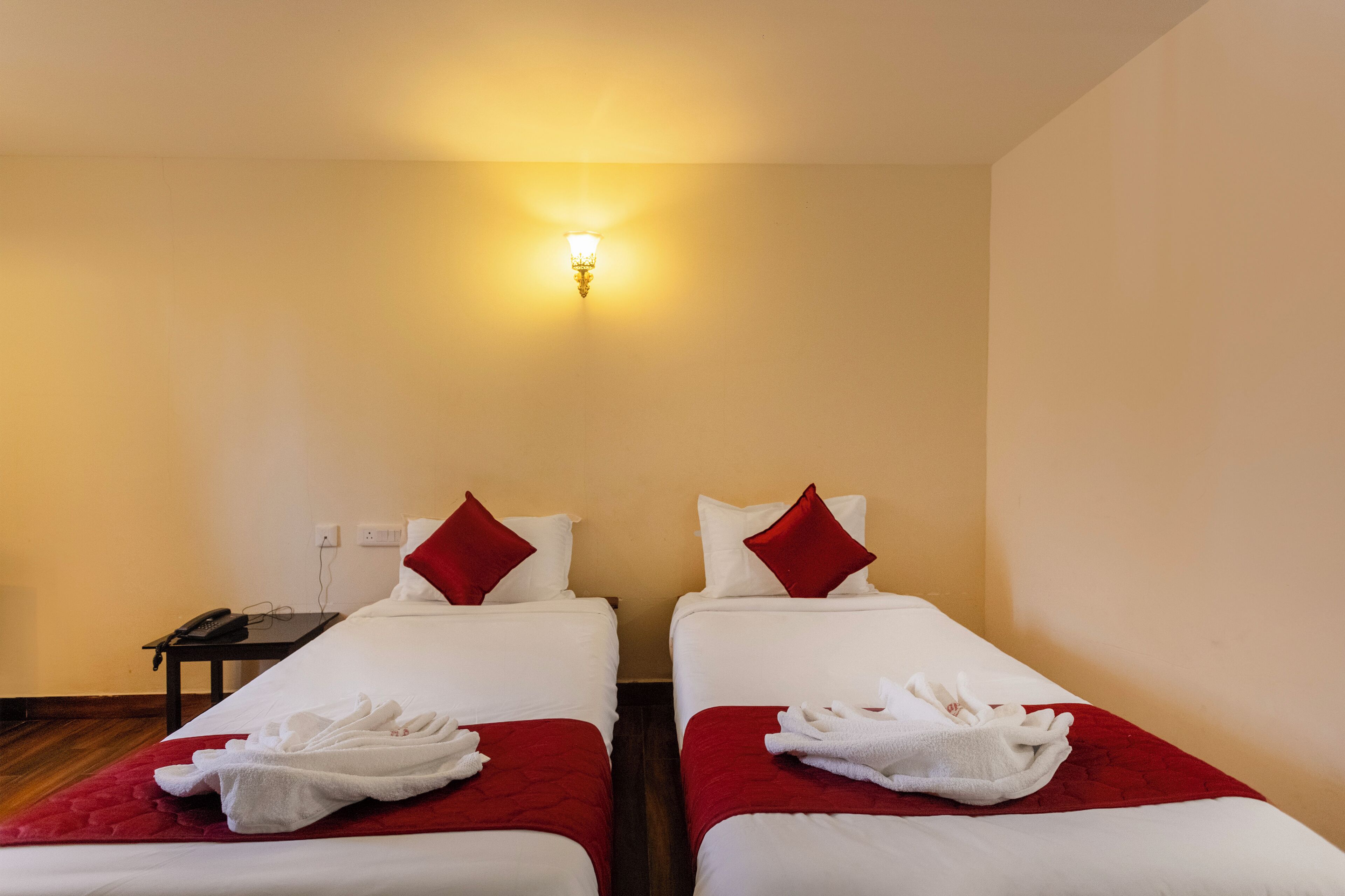 Habitación de hotel con dos camas, una mesita de noche con teléfono y una lámpara fijada a la pared.