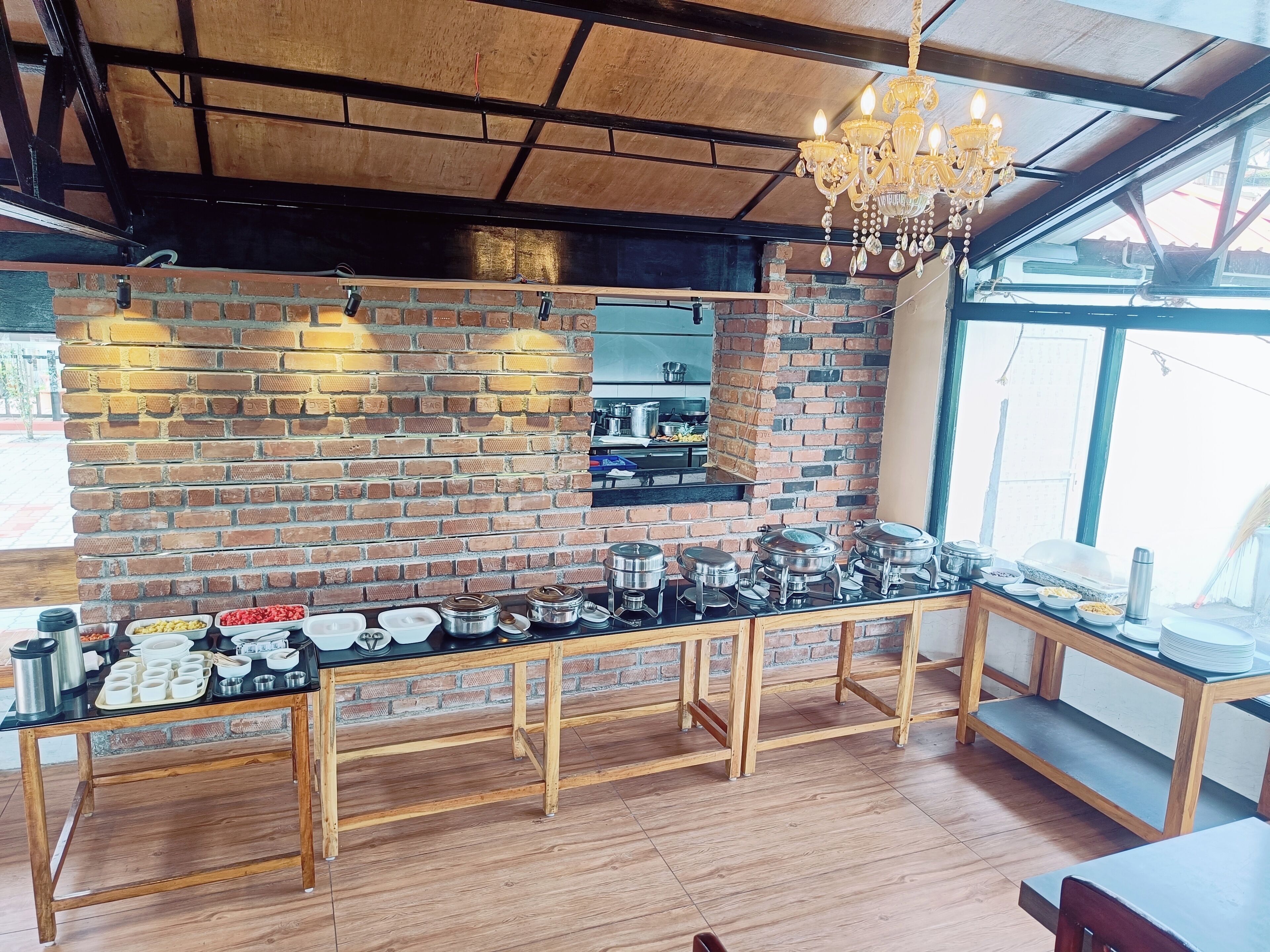 A kitchen with a brick wall, wooden counter, and a chandelier.