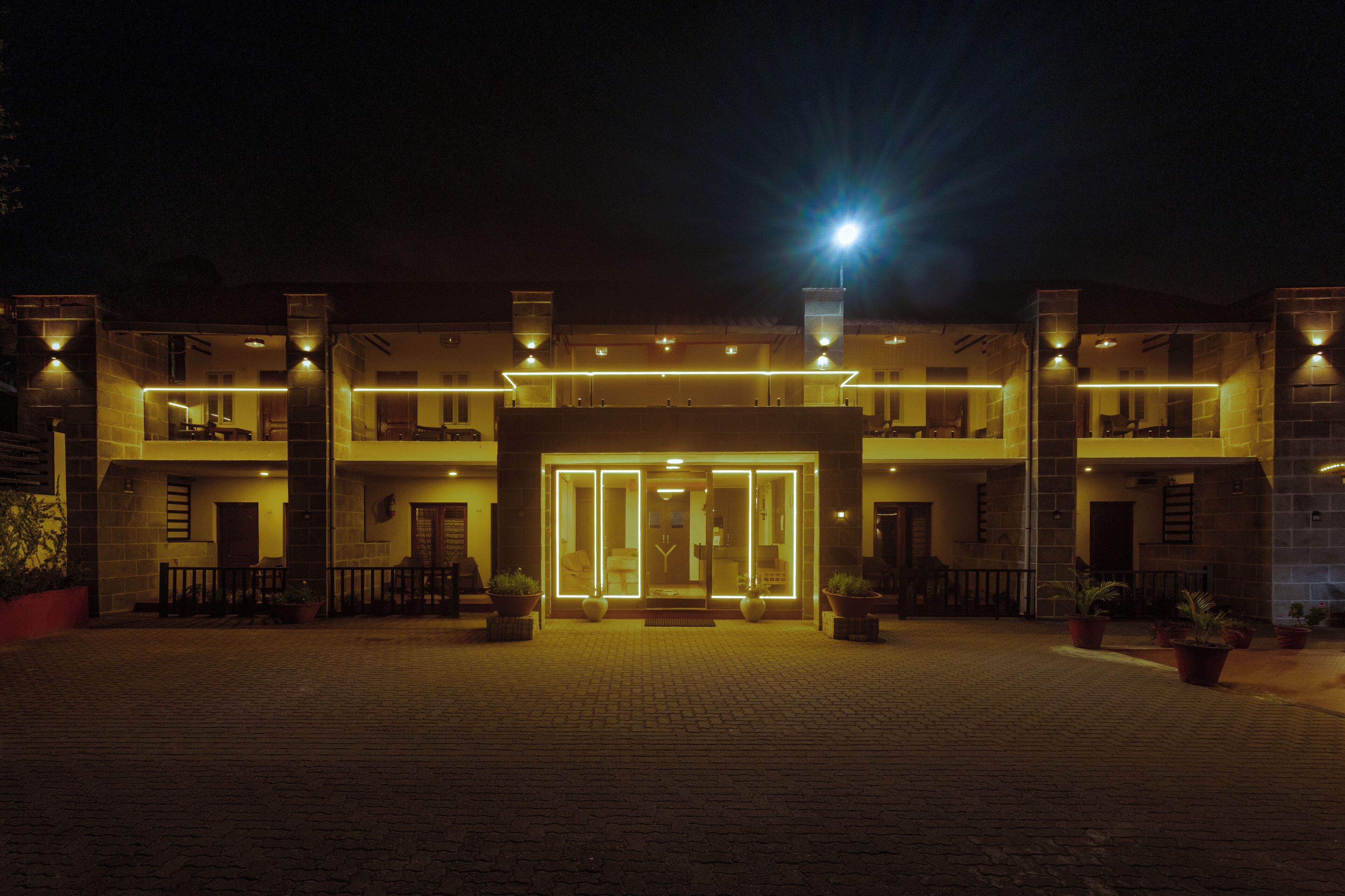 Ein Hotel mit Eingang, Glastür, Blumentöpfen und einem Pflasterweg.