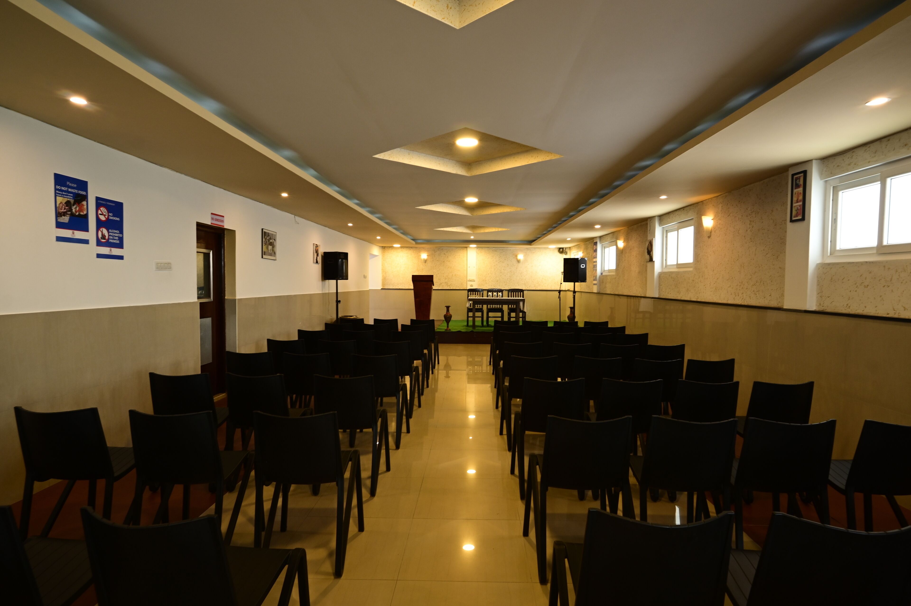 Un salón de conferencias con filas de sillas, un atril y altavoces en pedestales.