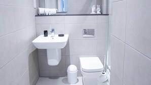 Une salle de bain moderne avec un lavabo blanc, un miroir et des toilettes.