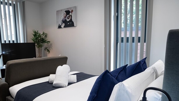Une chambre d’hôtel moderne, équipée d’un lit, d’une télévision et ornée d’un tableau au mur.