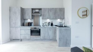A modern kitchen with grey cabinetry, a built-in oven, microwave, and kettle. - Two-bedroom by Leeds Art Gallery by Belvilla (Leeds)