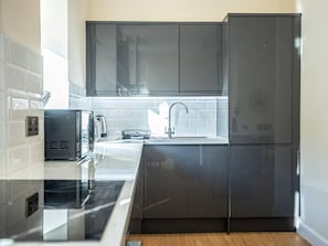 A modern kitchen with dark cabinets, a stainless steel countertop, and a built-in sink. - City Chic Christchurch 2BR Apartments by Sojo Stay (Ipswich)