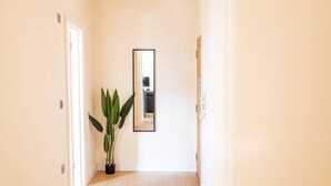 A hallway with a potted plant, a mirror, and a door leading to another room. - City Chic Christchurch 2BR Apartments by Sojo Stay (Ipswich)