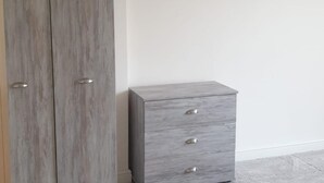 Una habitación con un armario gris y una cómoda a juego frente a una pared lisa.